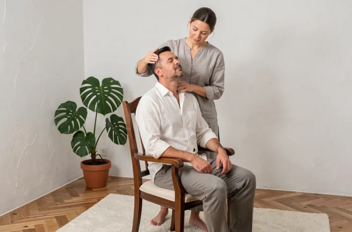 Homme recevant un massage crânien et cervical dans un studio de bien-être épuré avec sol en chêne